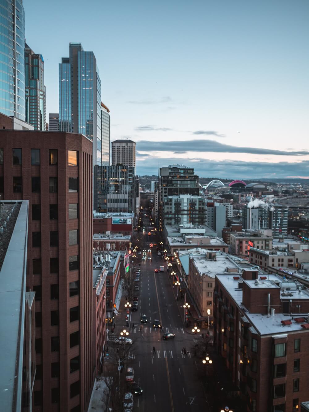 A view of a street cutting through  Seattle with cars, streetlights, and storefronts.