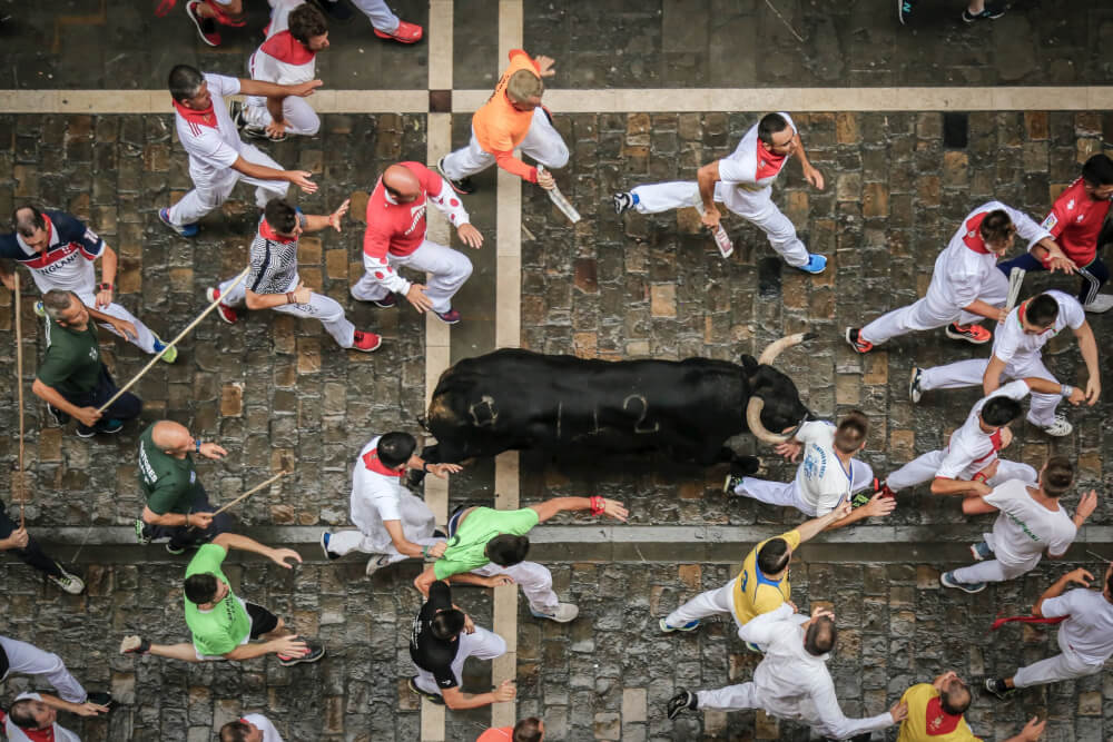 People running with the bull. One man is only a few inches away from the bulls horn.