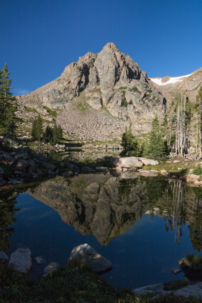 A mountain reflected in a lake on a beautiful blue sky day. 