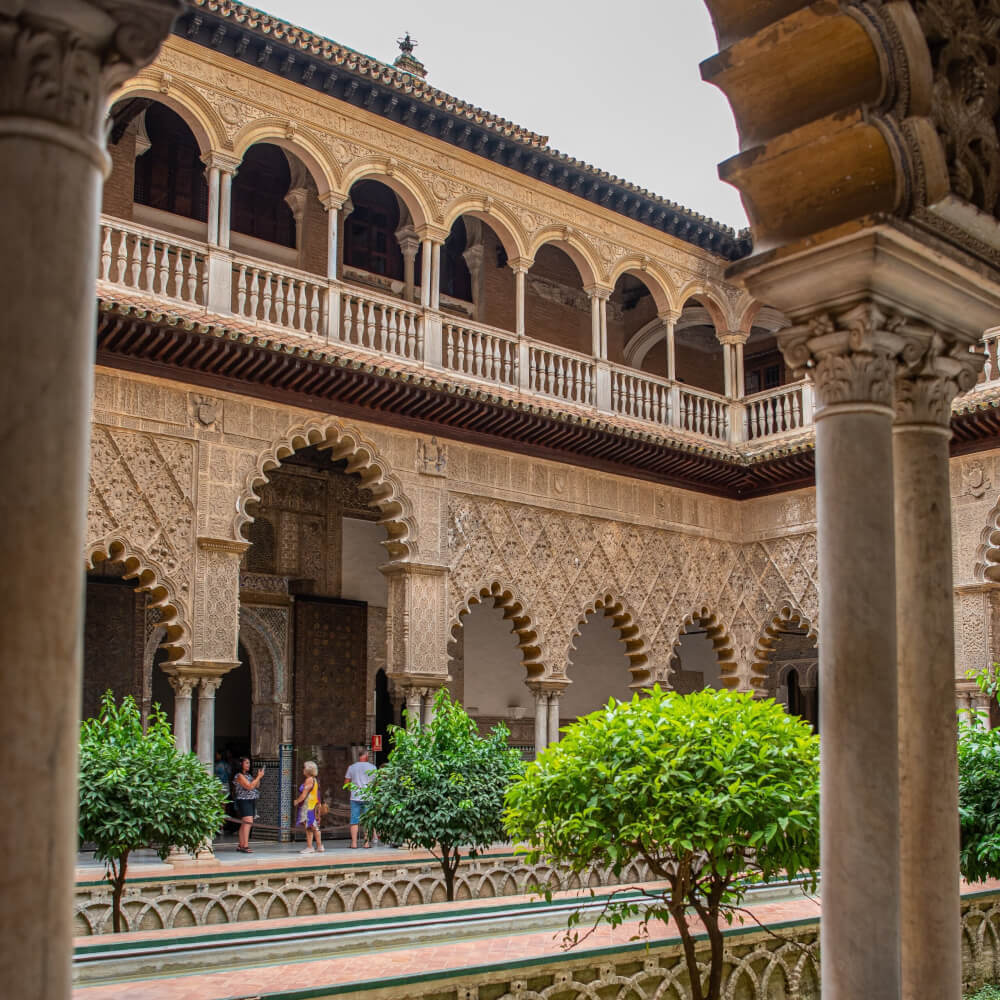 Courtyard with a reflecting pool, trees, a balcony, and many archways