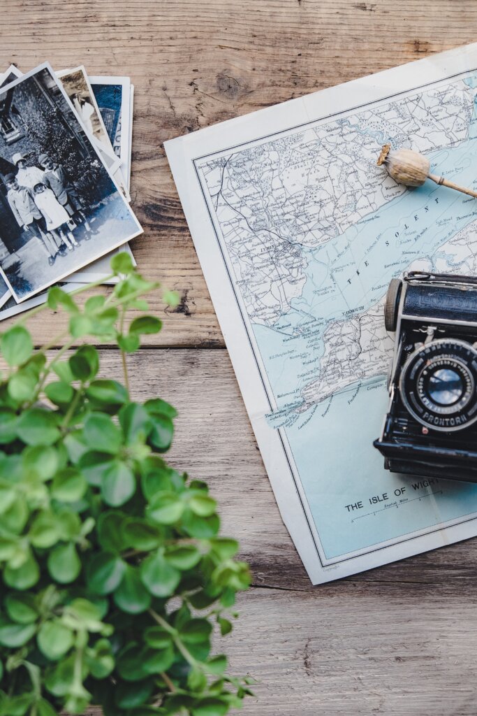 Photos and camera on top of a map on a wooden table