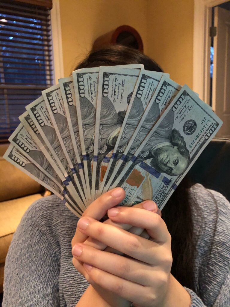 Woman holding stack of 100 dollar bills