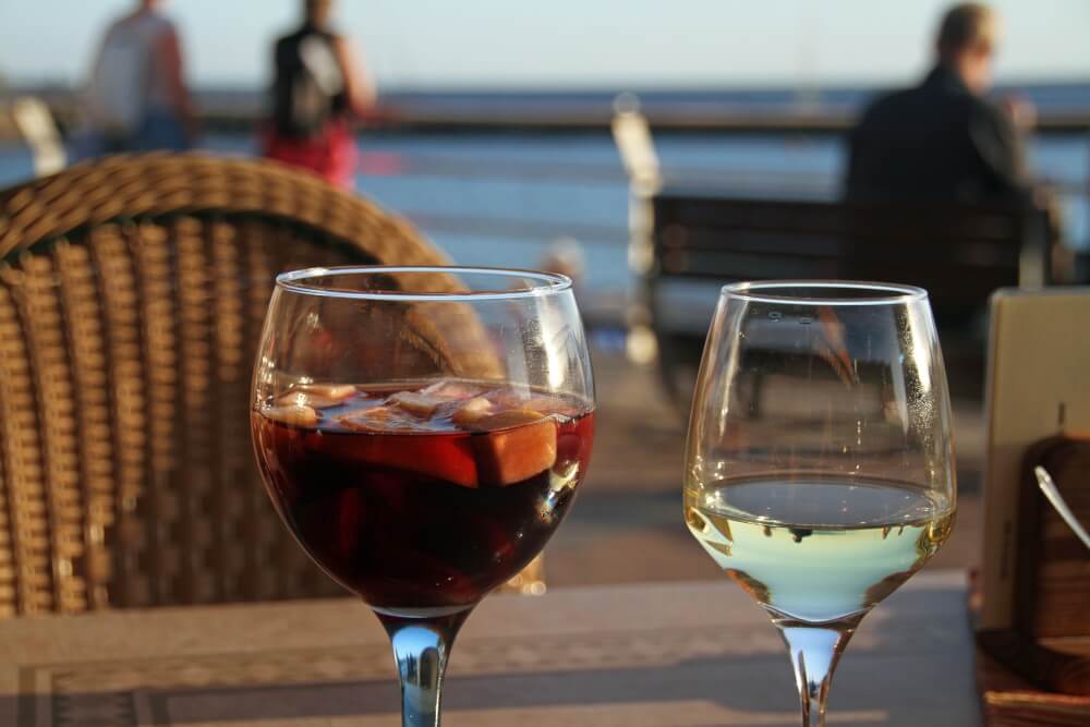 A glass of white wine and sangria at a table at an outdoor restaurant